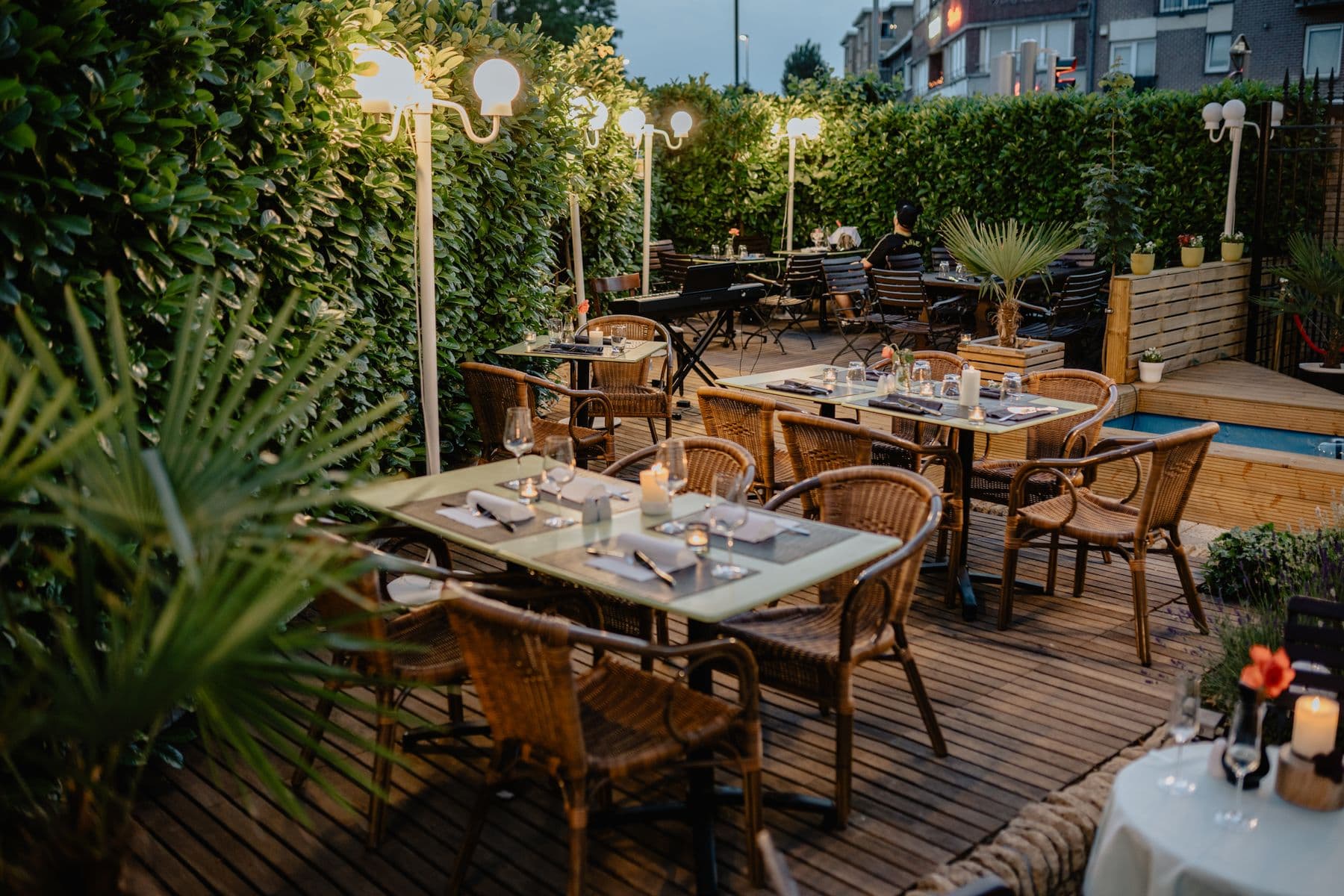Placeholder patio atmosphere: a leafy terrace with woven chairs and candlelit tables
